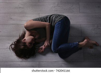 Battered young woman lying on floor
