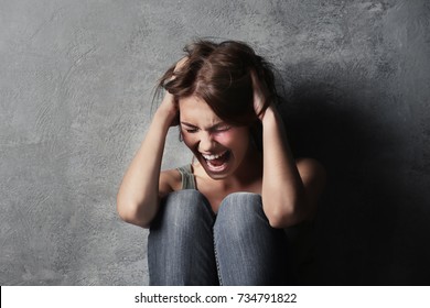 Battered young woman sitting near concrete wall