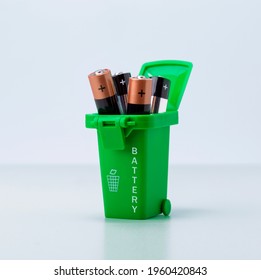 Baterías en recipientes de plástico verde sobre fondo gris claro. Concepto de reciclado de desechos tóxicos y cuestiones ecológicas de las baterías.