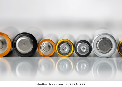 Baterías alineadas en una fila sobre un fondo blanco, antiguas pilas alcalinas y salinas usadas para un solo uso