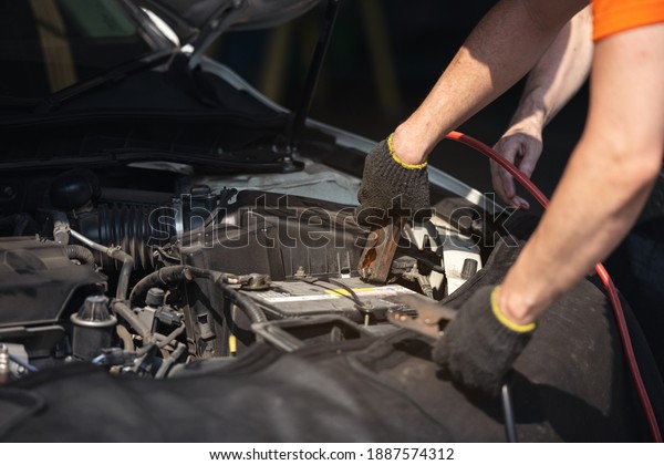 Battery charger and car in auto\
repair shop,Auto mechanic working in garage. Repair\
service.