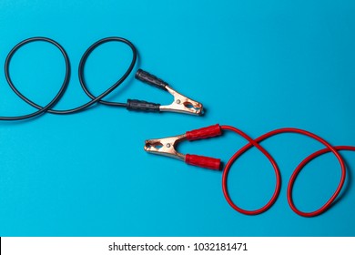 battery jumper cables on light blue background, red and black are parallel to each other