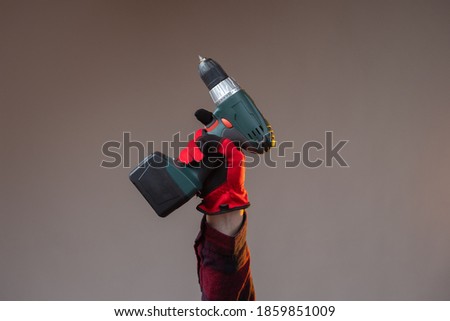Battery-powered screwdriver in the outstretched hand of a person. Wireless screw driver. Battery-powered screwdriver. Construction equipment. Carpentry equipment.