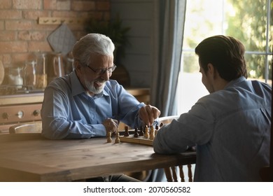 Battle at chessboard. Enthusiastic old father play friendly chess match at home with grownup son. Happy diverse generation male relatives elder younger passionate players meet at chessboard on weekend - Powered by Shutterstock