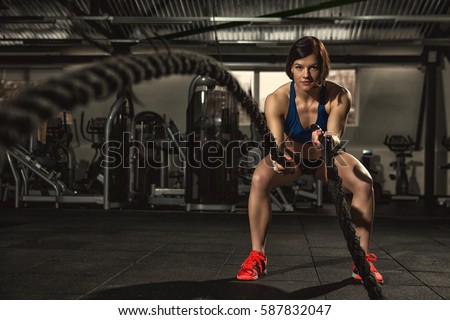 Battle ropes session. Attractive young fit and toned sportswoman working out in functional training gym doing crossfit exercise with battle ropes copyspace battling ropes cross-fit workout motivation