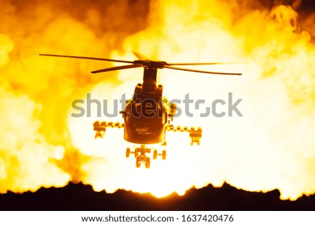 Battle scene with toy helicopter and fire at background
