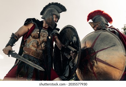Battle With Swords Between Two Ancient Greek Or Roman Warriors In Battle Dress Against Sky Background.