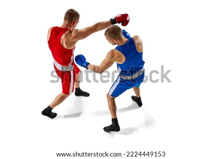 Battle of two boxers. Two muscular professional boxers in blue and red sportswear training isolated on white background. Concept of sport, competition, training, energy. Aerial view