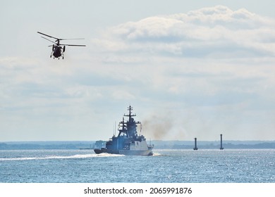 Battleship war ship corvette during naval exercises and helicopter maneuvering over water in Baltic Sea. Warships, helicopters and boats perform tasks in sea, military warships sailing, Russian Navy