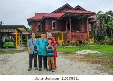 Batu Pahat, Malaysia - May 3rd, 2022 :  Happy Malay Family In Traditional Clothing And Traditional Malay House During Hari Raya. Malaysian Family Lifestyle At Home. Happiness Concept.