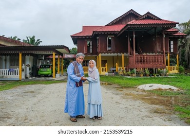 Batu Pahat, Malaysia - May 3rd, 2022 :  Happy Malay Family In Traditional Clothing And Traditional Malay House During Hari Raya. Malaysian Family Lifestyle At Home. Happiness Concept.