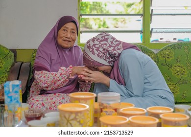 Batu Pahat, Malaysia - May 3rd, 2022 :  Happy Malay Family In Traditional Clothing And Traditional Malay House During Hari Raya. Malaysian Family Lifestyle At Home. Happiness Concept.