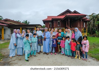 Batu Pahat, Malaysia - May 3rd, 2022 :  Happy Malay Family In Traditional Clothing And Traditional Malay House During Hari Raya. Malaysian Family Lifestyle At Home. Happiness Concept.