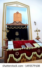 Batumi, Georgia - May 16, 2018: The wooden altar in prayer area with menorah hanukkah candle and black drape inside synagogue. Note the red and black velvet cloth and star of David. 