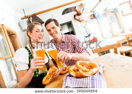 Bavarian couple wearing traditional dress, flirting and  drinking beer in restaurant