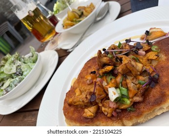 Bavarian Dish Of Schnitzel With Chanterelle Mushrooms Served With Fried Potatoes And A Green Salad In Seperate Bowls