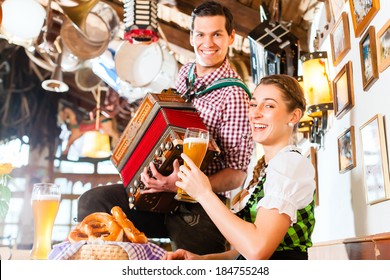 Bavarian man playing folk music for woman wearing dirndl