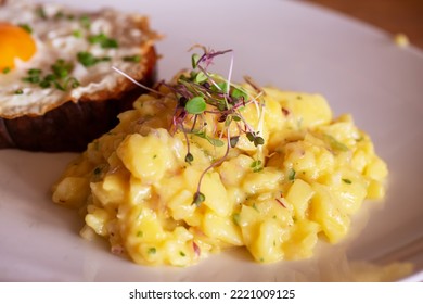 Bavarian Potato Salad On A White Plate. Meat Loaf Or Liver Loaf With Fried Egg In The Background. Natural Light, Selective Focus. 