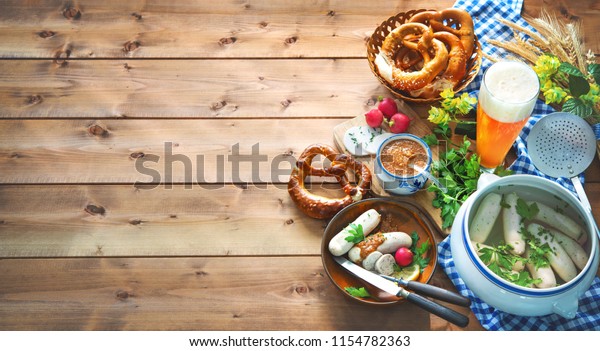 Bavarian sausages with pretzels,\
sweet mustard and beer on rustic wooden table. Oktoberfest\
menu