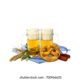 Bavarian Soft Salted Pretzels, Wheat Ears, Sausages, Mugs Of Lager Beer, Green Hop Cones And Blue And White Doily And Ribbon On White Background With Space For Text. Oktoberfest