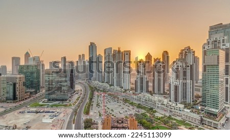 Bay Avenue during sunset with modern towers residential development in Business Bay aerial panoramic timelapse, Dubai, UAE. Skyscrapers with traffic on a road near big parking lot
