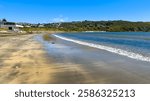 Tītahi Bay beach, Porirua, Wellington, New Zealand. Surf Life Saving Club at left, boatsheds and houses in distance. Panoramic view.