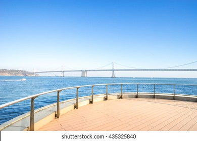 bay bridge over tranquil water in blue sky on view from empty brick floor
