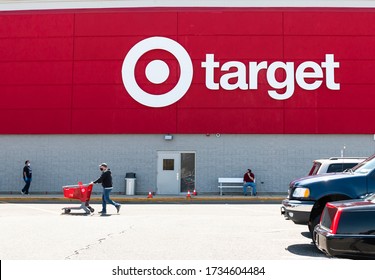 Bay Shore, New York, USA - 25 April 2020: The Logo Of A Target Store On The Buildings Exterior Facing The Parking Lot With People Wearing Face Masks And Gloves.