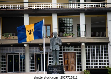Bay Street, St. Michael, Barbados - August 19th 2021: Statue of Sir Grantley Herbert Adams, the first premier of Barbados, with a Barbadian flag in front of Barbados Government Headquarters