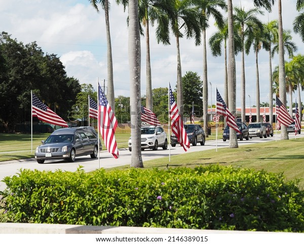 Bayamon, Puerto Rico - April 13, 2022: National\
Cemetery veteran funeral procession service being escorted down the\
avenue of flag.