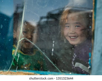 Bayan Ulgii, Mongolia, 28th September 2015: Mongolian Kids Looking Out Of A Broken Window