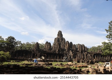 Bayon Temple's towering stone faces gaze serenely in all directions, intricately carved into massive blocks. The temple's maze-like corridors evoke mystery amidst ancient Cambodian jungle. - Powered by Shutterstock