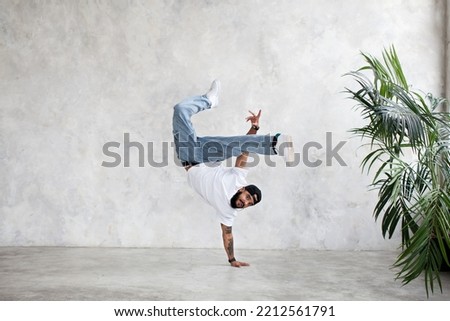 B-Boy performing one handed freeze. Guy breakdancer stands on arm and lifted legs up. Hip hop dance Stock fotó © 