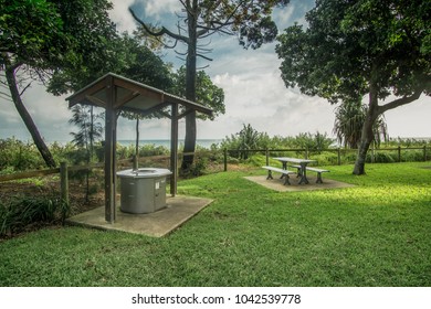 BBQ Area With A Park Bench Surrounded By Trees & Lush Green Grass By The Beach At Torquay,Hervey Bay,Queensland, Australia