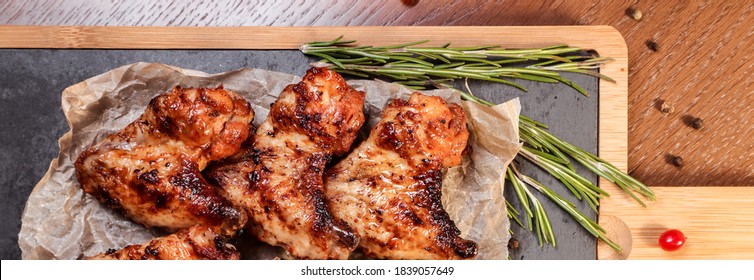 BBQ Chicken Wings On Coals With Sauce On A Wooden Board.