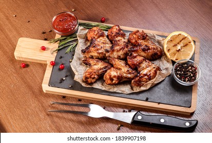 BBQ Chicken Wings On Coals With Sauce On A Wooden Board.