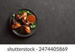 Bbq chicken wings on plate over dark stone background with copy space. Tasty grilled chicken meat for dinner. Top view, flat lay