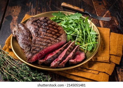 BBQ dinner with top sirloin beef steak and salad on a plate. Wooden background. Top view.