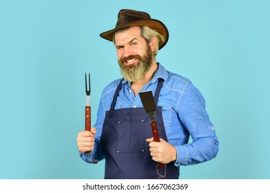 Bbq food. Tools roasting meat. Man in apron hold barbecue grill. Hipster dyed beard promoting bbq equipment. Cooking healthy. Cooking utensils. Summer picnic. Bbq american tradition. Culinary concept.