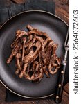 BBQ Fried beef tender strips, sliced steak in a plate. wooden background. top view.