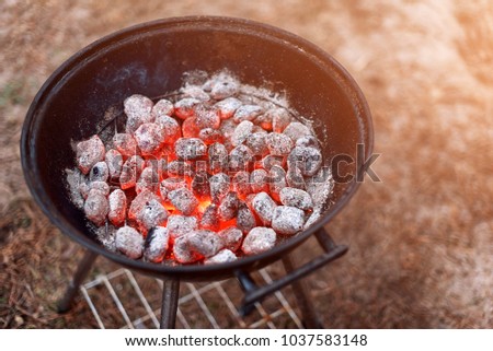 BBQ grill with glowing and flaming hot charcoal briquettes, closeup, top view.