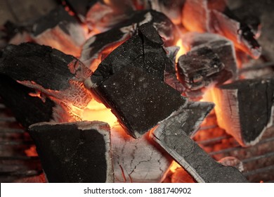 BBQ Grill Pit With Glowing And Flaming Hot Charcoal. Glowing Hot Charcoal In Barbecue Grill Pit With Flames Background Texture, Close-up. Flaming Charcoal In Grill Pit Isolated On Black Background.