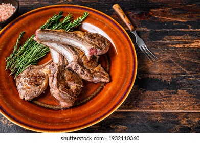 BBQ grilled lamb mutton meat chops steaks on a plate. Dark wooden background. Top view. Copy space.