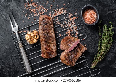 BBQ grilled Lamb tenderloin fillet meat on grill, mutton loin steak. Black background. Top view