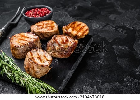 BBQ grilled pork medallions steaks, tenderloin fillet meat. Black background. Top view. Copy space