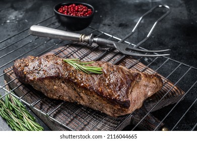BBQ grilled tri tip beef steak on a grill. Black background. Top view