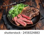 BBQ Grilled Wagyu New York beef meat steak or Striploin steak in a plate with salad. Wooden background. Top view.