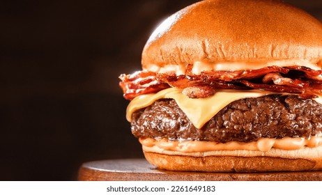 BBQ hamburger on a serving board. Above view table scene on a dark wood background with copy space bacon