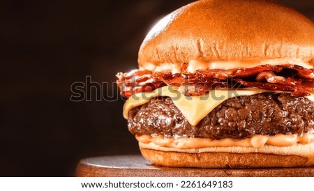 BBQ hamburger on a serving board. Above view table scene on a dark wood background with copy space bacon