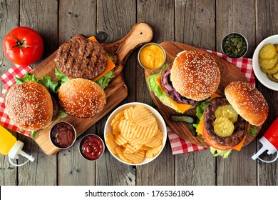 BBQ Hamburger Table Scene. Top View Over A Dark Wood Background.